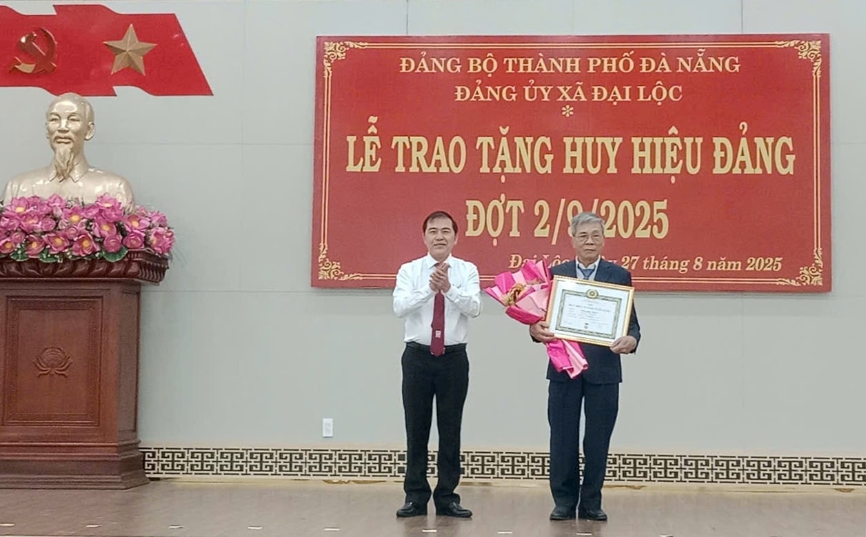 Phó Trưởng ban Thường trực Ban Tổ chức Thành ủy Nguyễn Đức Nam (bên trái) trao Huy hiệu Đảng cho đảng viên thuộc Đảng bộ xã Đại Lộc. Ảnh: NGUYỄN TUYẾT