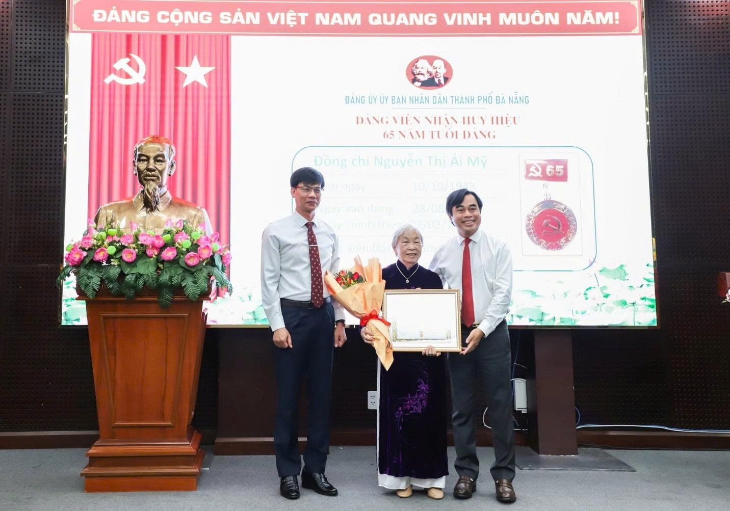 Phó Bí thư Đảng ủy UBND thành phố Tô Văn Hùng (bên phải) và Phó Trưởng ban Tổ chức Thành ủy Trần Hải Vân (bên trái) trao Huy hiệu 65 năm tuổi Đảng cho đảng viên. Ảnh: NGỌC PHÚ