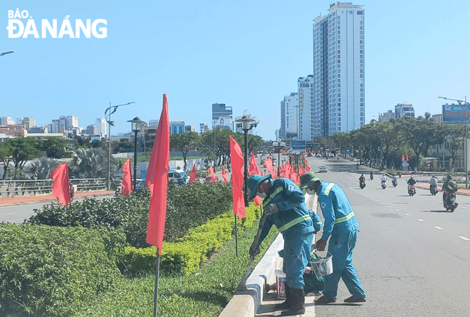 workers of the da nang park company paint the median strip